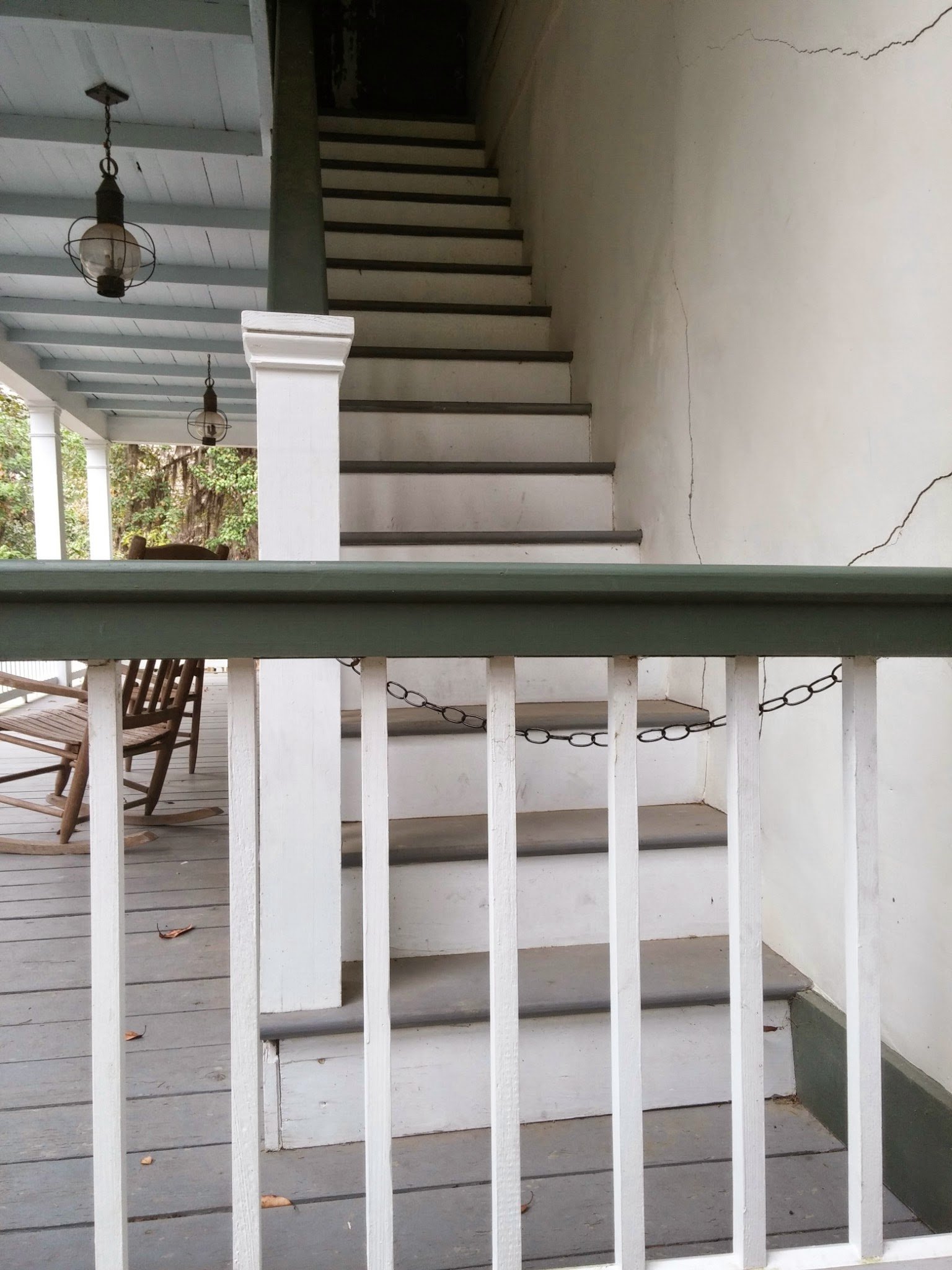 A porch railing with rows of plain wooden balusters