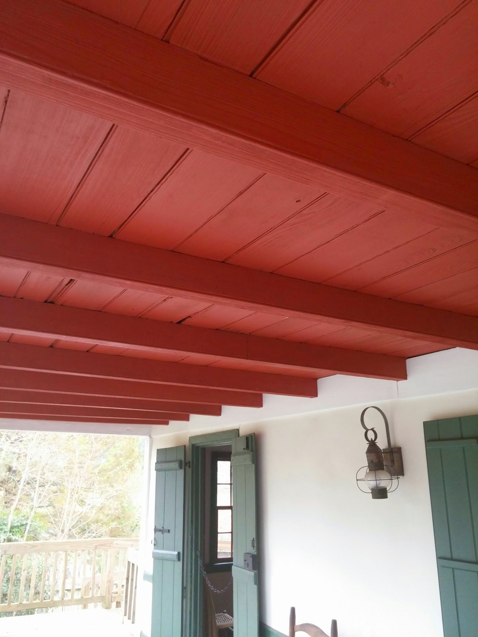 A porch ceiling painted soft red over exposed boards